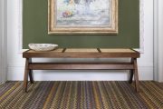 Multicoloured herring bone carpet with green wall, picture frame and bench.